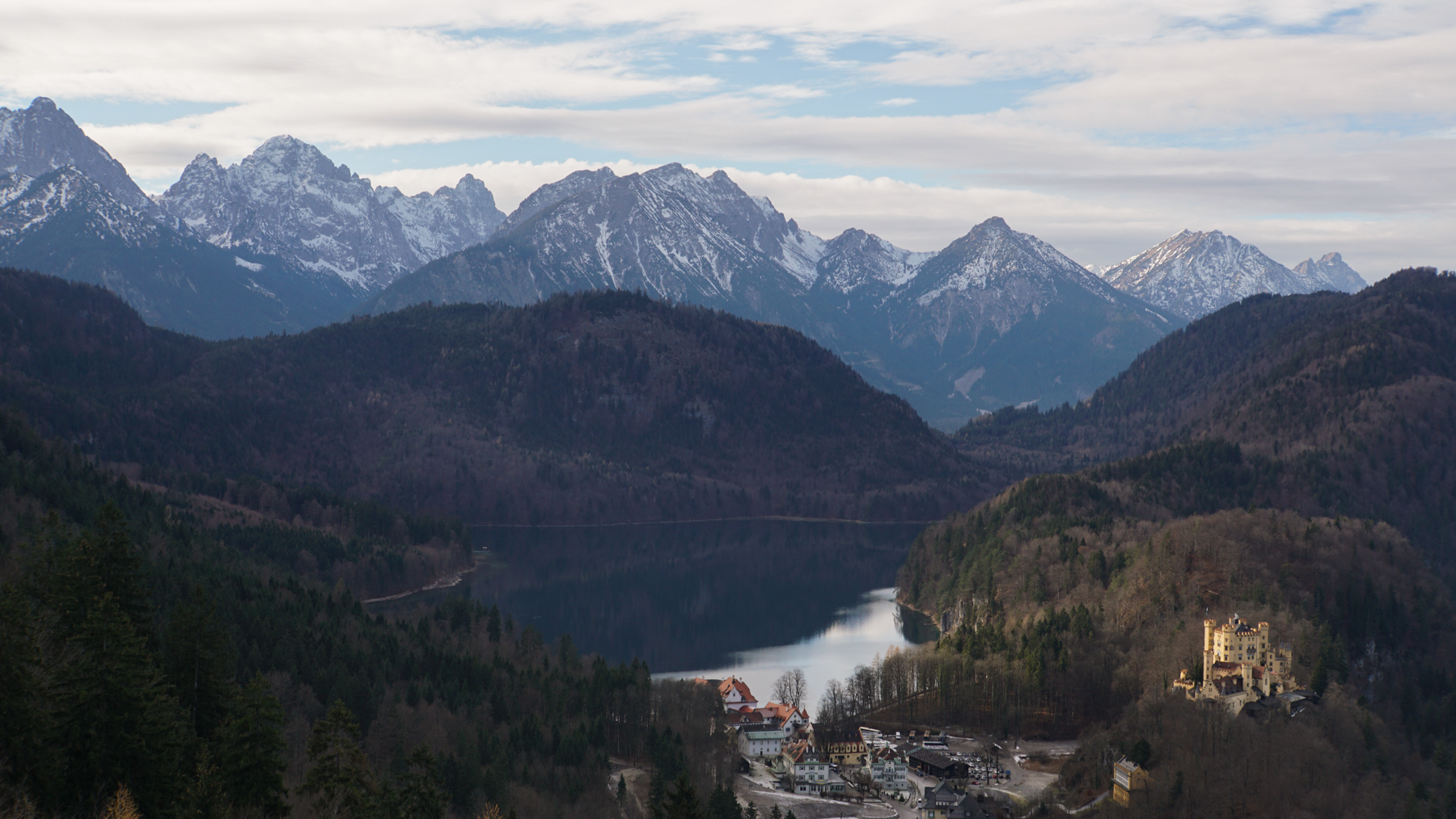 A landscape view of the Bavarian mountains with a small village and castle in the foreground